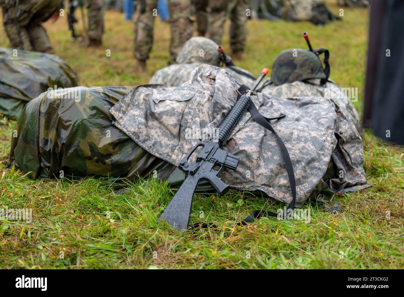 Modernes schwarzes Militärgewehr, das sich an einem nassen Rucksack stützt Stockfoto