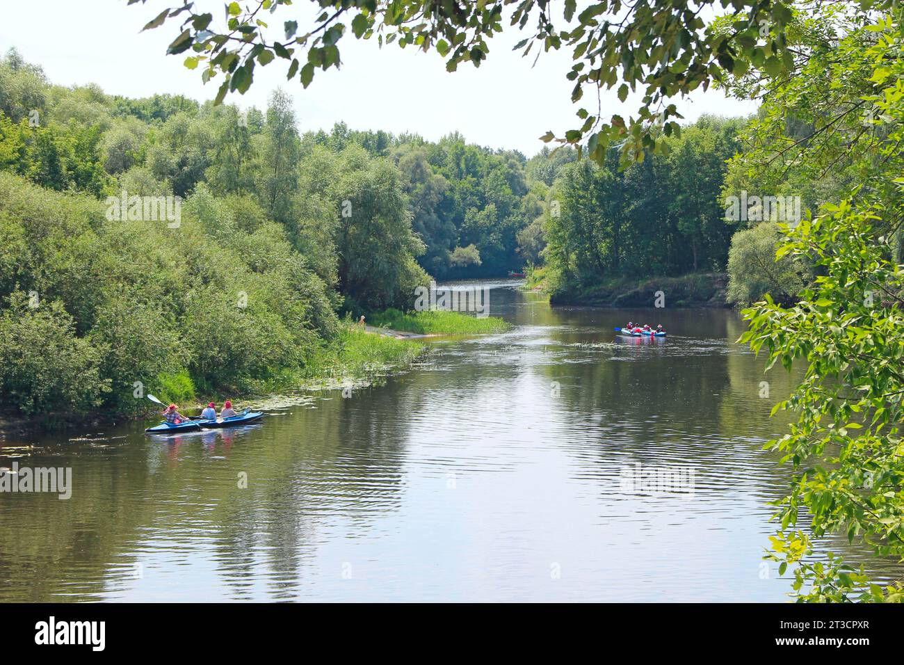 Eine Gruppe von Menschen segelt auf Kajaks entlang eines wunderschönen Flusses. Sommerferien. Sport und Erholung auf dem Fluss im Sommer. Kajakfahren auf dem Fluss. Stockfoto