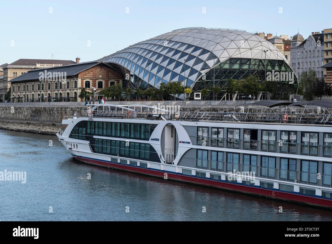 Flusskreuzfahrtschiff vor dem ehemaligen Lagerhaus in Budapest, Ungarn Stockfoto