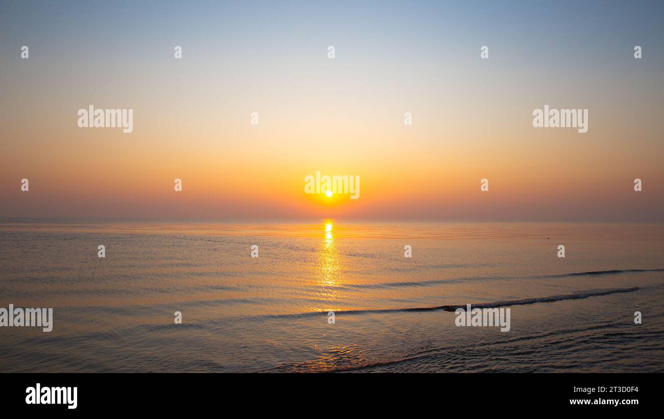 Sonnenuntergang im Meer mit sanften, sanften Wellen und Reflexion im Wasser Stockfoto