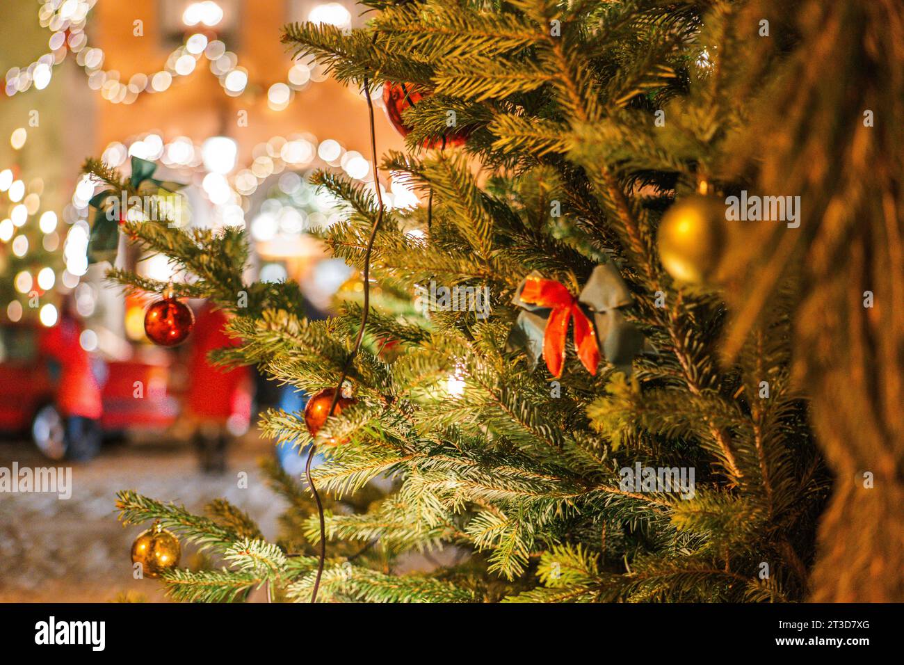 Weihnachtliche Stadt im Hintergrund. Weihnachtsbaum mit Girlanden und Menschen, die aus dem Blickfeld geraten Stockfoto