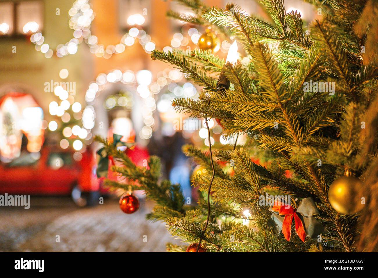 Weihnachtliche Stadt im Hintergrund. Leuchtende Läden und Weihnachtsdekorationen auf den Straßen Deutschlands. Weicher Fokus. Weihnachtsbaum mit Girlanden und Menschen Stockfoto