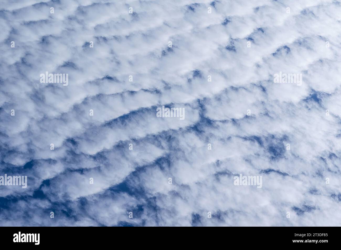 Das Foto fängt die ruhige Schönheit eines klaren blauen Himmels mit flauschigen weißen Wolken ein. Stockfoto