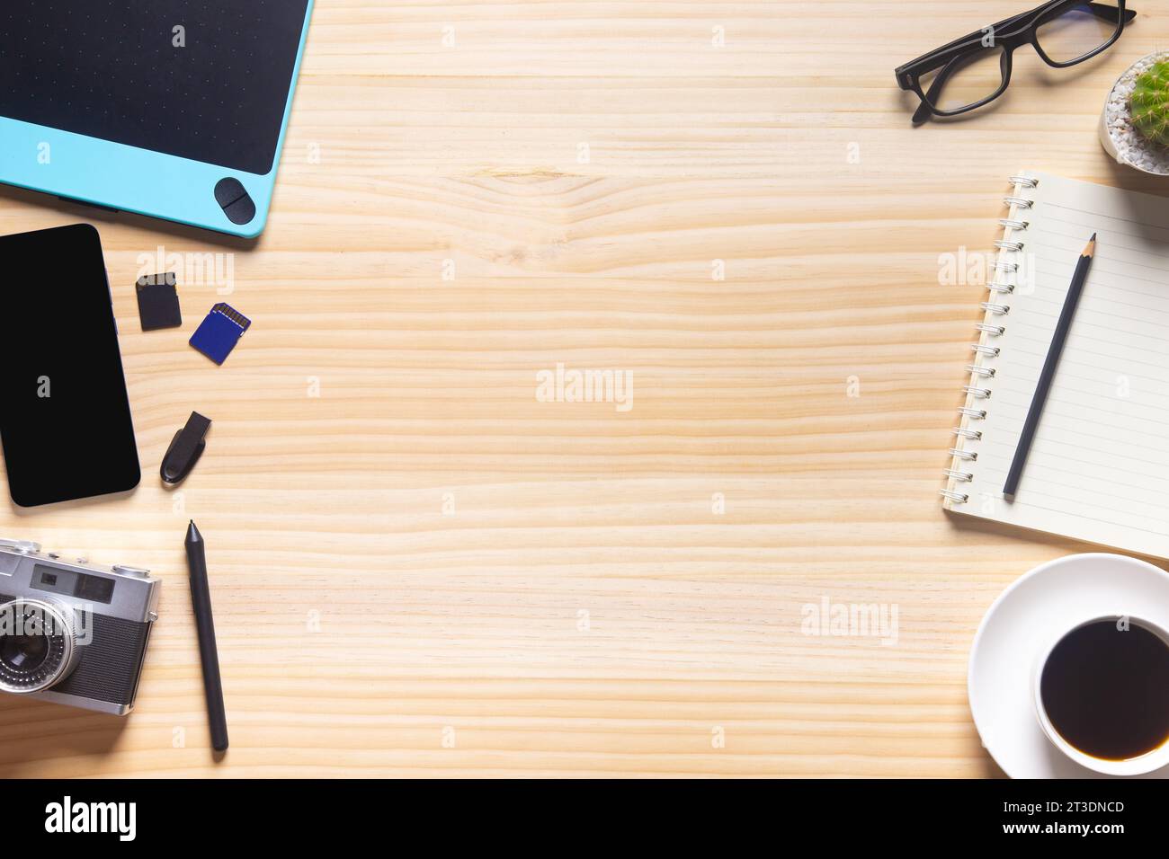 Holzschreibtischbüro mit Laptop, Smartphone und anderen Arbeitsmaterialien mit einer Tasse Kaffee. Draufsicht mit Kopierraum für die Texteingabe. Arbeitsbereich des Konstrukteurs o Stockfoto