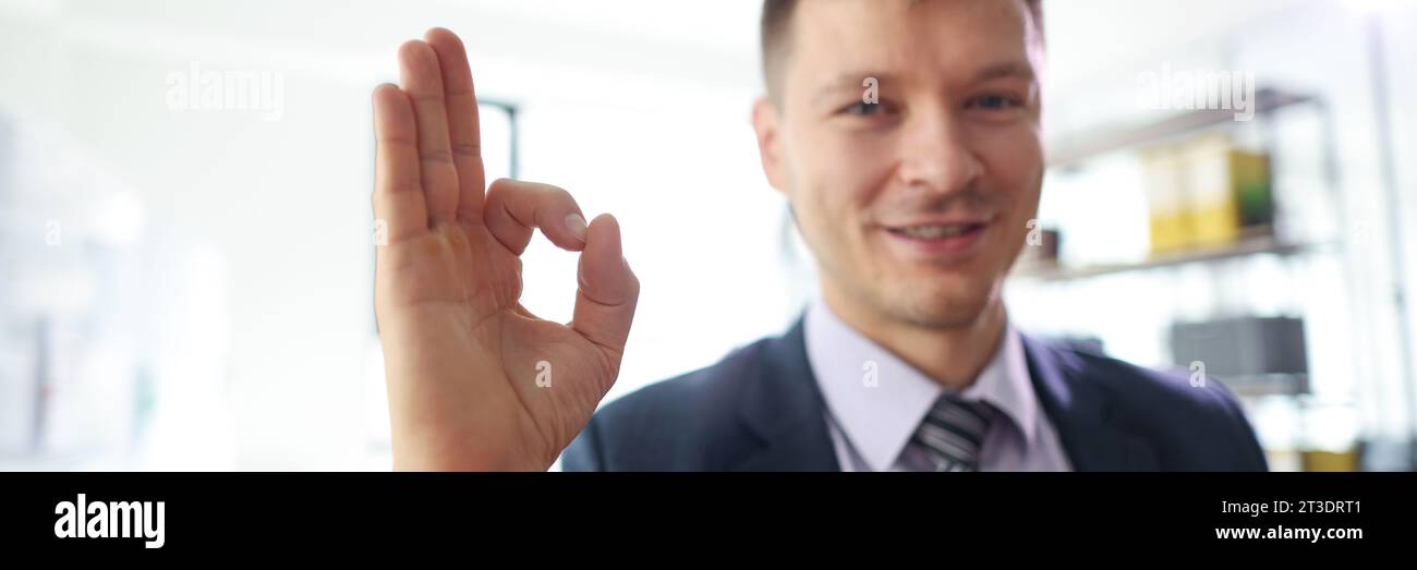 Ein lächelnder Geschäftsmann zeigt das "OK" -Schild im Büro Stockfoto