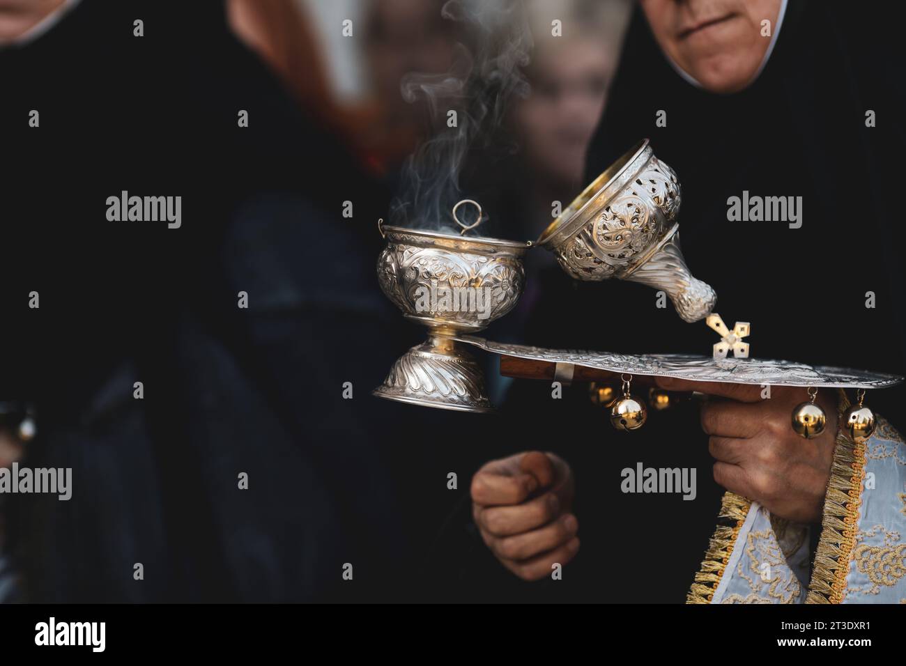 Details mit geringer Tiefenschärfe (selektiver Fokus) mit der Hand einer orthodoxen christlichen Nonne, die einen rauchenden, metallischen Räucherhaken in der Hand hält Stockfoto