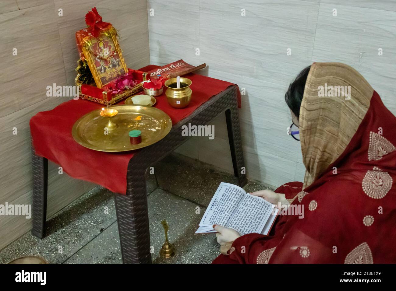 indische Frauen singen heilige Mantren zu Hause für spirituelles Wohlbefinden aus verschiedenen Blickwinkeln anlässlich der durga Puja in indien. Stockfoto