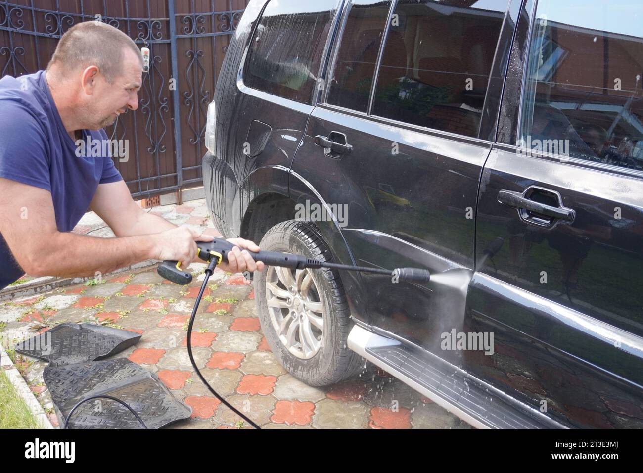 Man wäscht Auto mit Autowaschanlage - Hochdruckreiniger, Shampoo, Schwämme und Mikrofaser-Handtücher Stockfoto