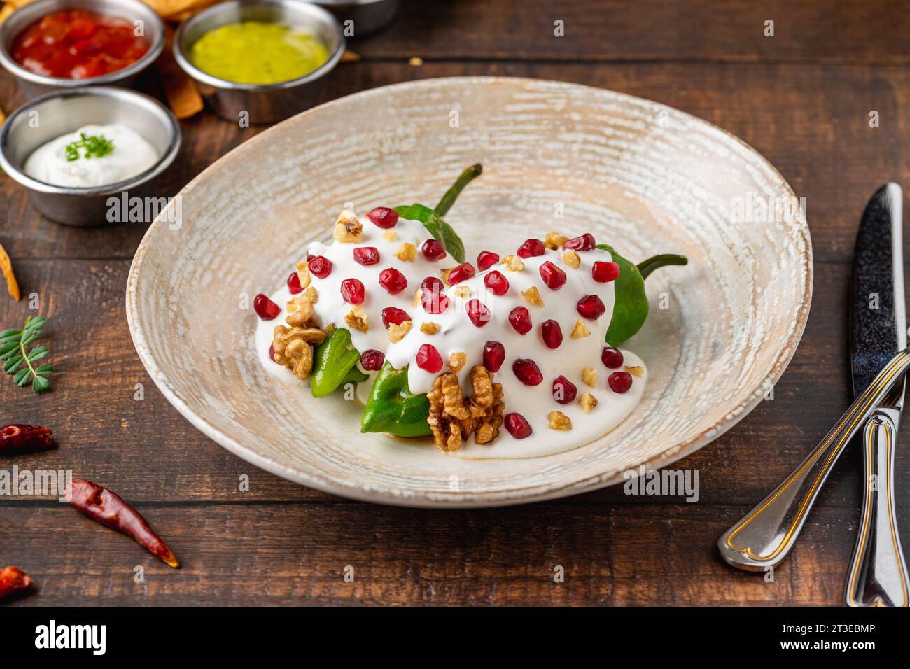 Chiles en Nogada, ein traditionelles mexikanisches Gericht mit Pablano-Chili, gefüllt mit Fleisch und Obst, garniert mit Granatapfelkernen und Walnüssen Stockfoto