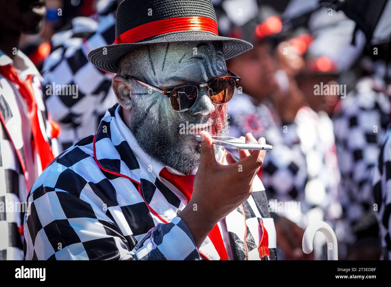 Teilnehmer des Karnevals in Kapstadt kommunizieren während einer Pause in Kapstadt während des Neujahrsfestes auf einem Handy oder Mobiltelefon Stockfoto