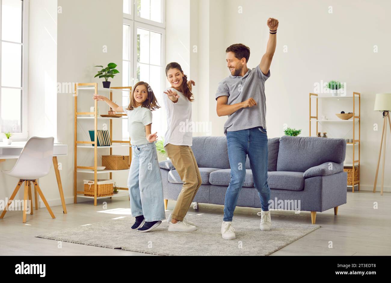 Glückliche, fröhliche Mutter, Vater und Tochter, die eine Party feiern und im Wohnzimmer tanzen Stockfoto
