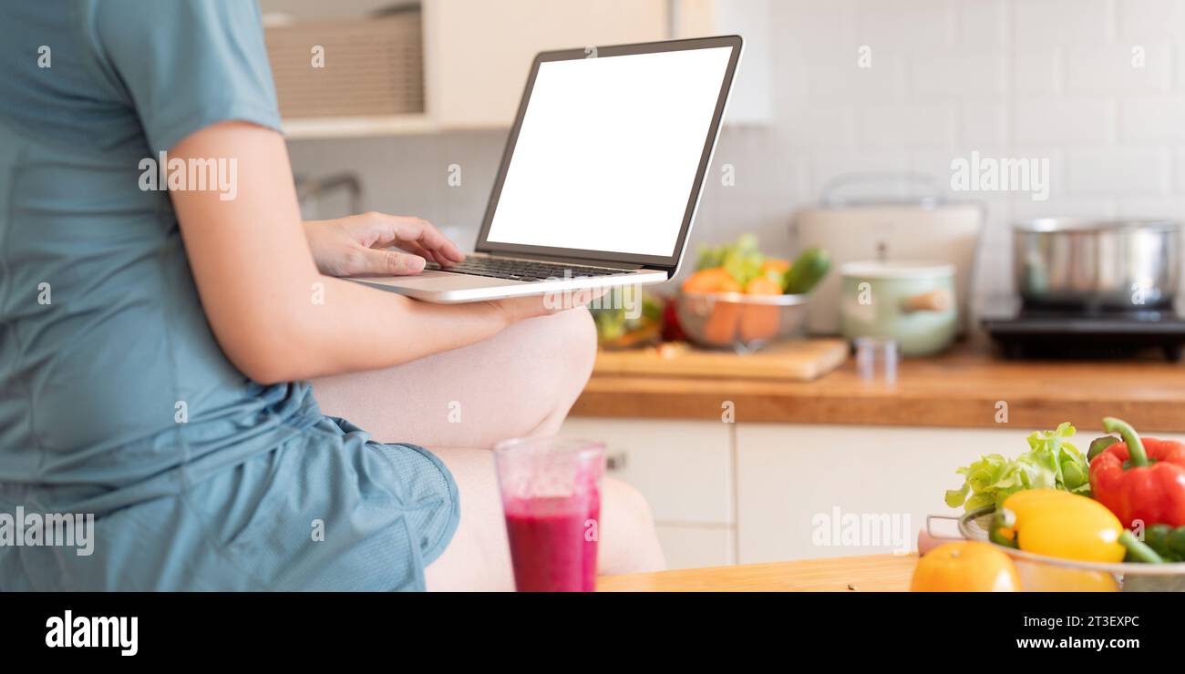 Frau mit persönlichem Laptop mit leerem Bildschirm mit Kopierraum, Tastatur, Suche nach neuen gesunden Rezepten online, Mock Up Stockfoto