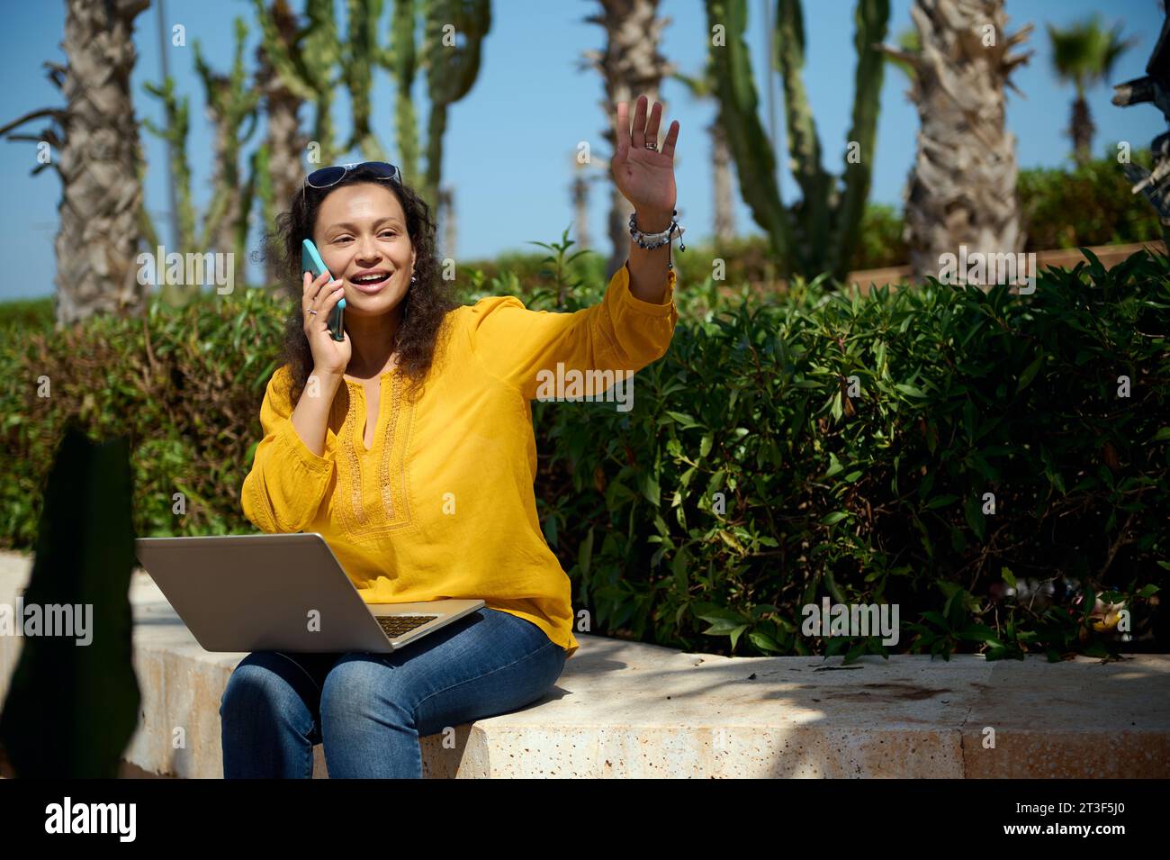 Lächelndes Multitasking beschäftigte glückliche junge Erwachsene Geschäftsfrau, in Freizeitkleidung, winkende Hand, Begrüßung, Gespräch mit Smartphones, Online-Workin Stockfoto