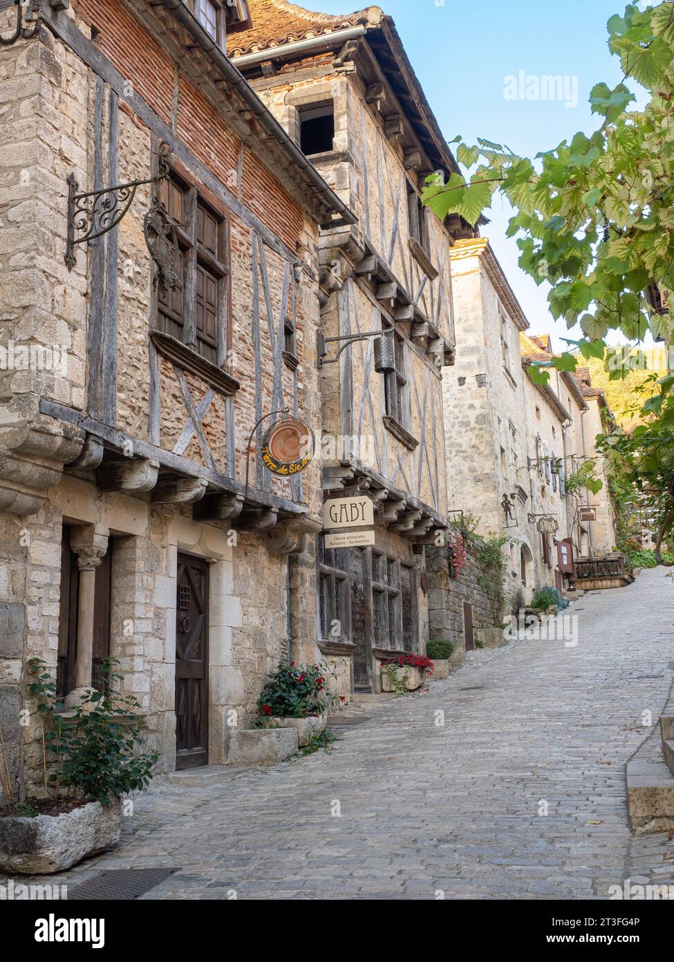 St. Cirq Lapopie, Lot, Frankreich. Blick auf die Kopfsteinpflasterstraße mit Geschäften und Restaurants. Stockfoto