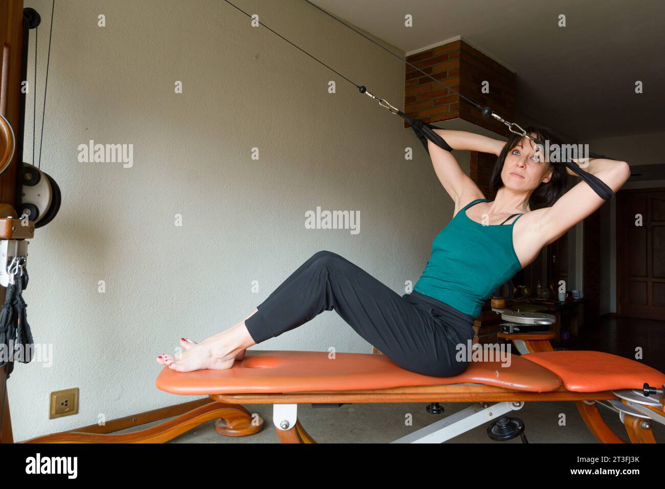 Lateinische Erwachsene Frau zu Hause trainiert Balance und Energie, stärkt Gelenke und Oberkörper- und Hüftmuskeln, sitzt auf einem Trainingsgerät. Kopierbereich. Stockfoto