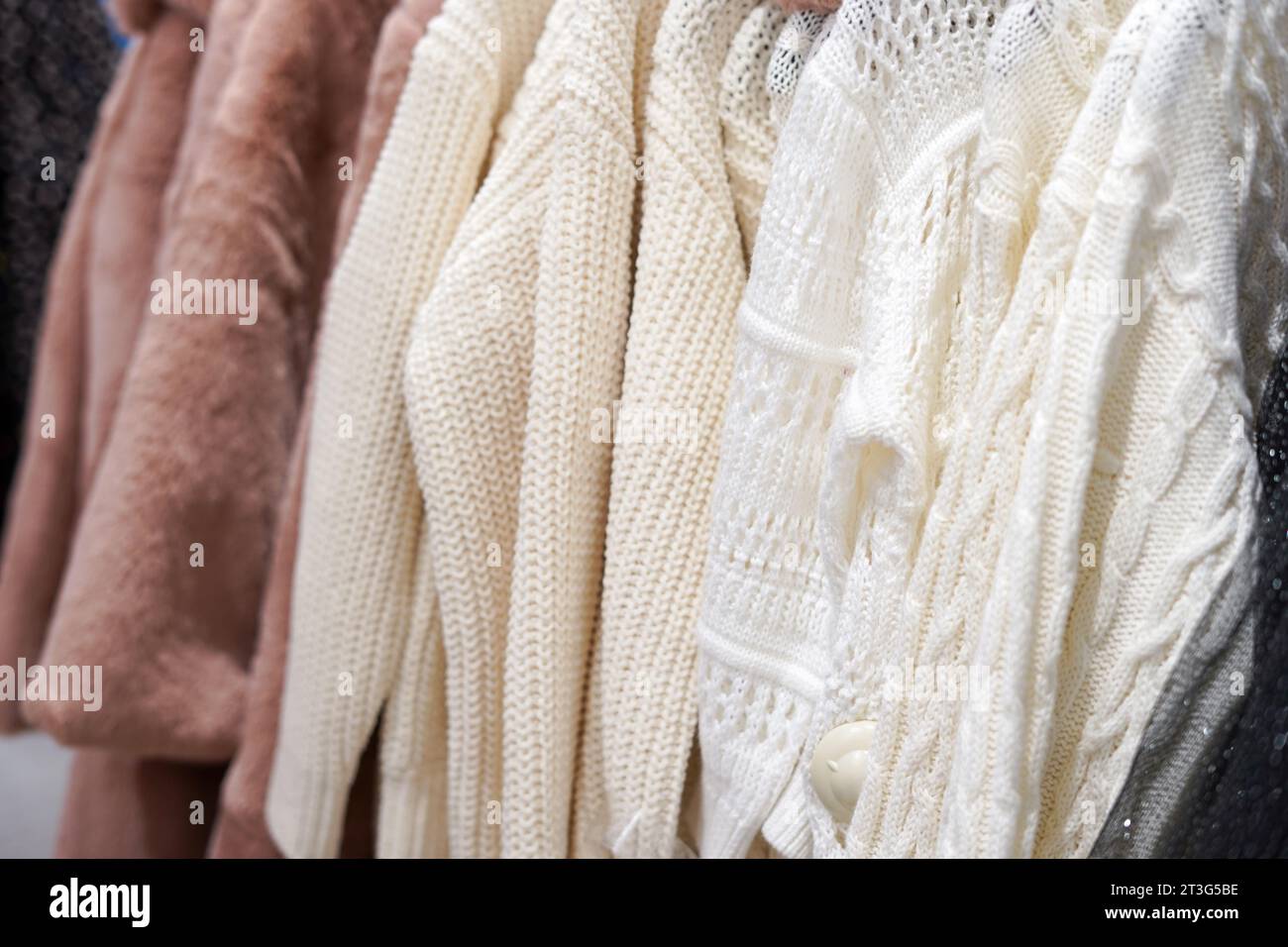 Leichte handgestrickte Pullover auf Kleiderbügeln in Großansicht. Modekonzept. Winterkleidung Stockfoto
