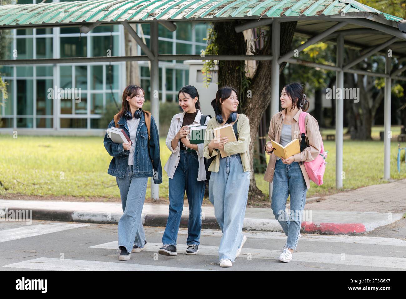 Eine Gruppe junger asiatischer Studenten, die vor dem Klassenzimmer an der Universität spazieren gehen und sich unterhalten. Bildung, wieder-zur-Schule-Konzept Stockfoto