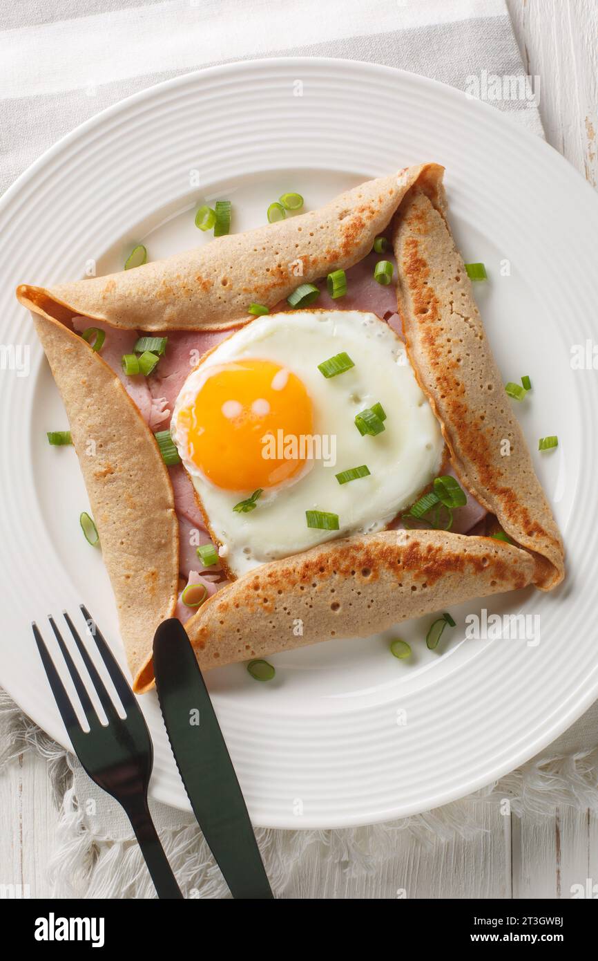 Buchweizen-Kreppegalette mit Schinken und Ei für leckeres gesundes Frühstück Nahaufnahme auf dem Teller auf dem Tisch. Vertikale Draufsicht von oben Stockfoto