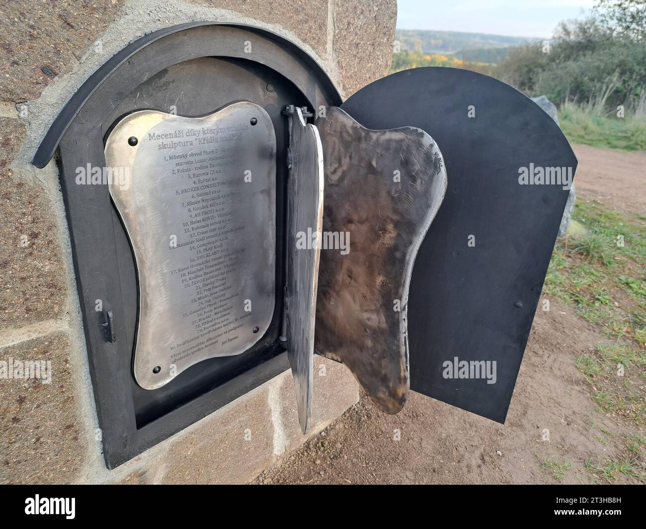 Eine Tür im Steinsockel der geschmiedeten Skulptur der Flügel der Hoffnung am malerischen Aussichtspunkt Koterov über Pilsen, Tschechische Republik, dargestellt am 25. Oktober 2023. Das sieben Meter hohe Werk hat eine Metalltür in einem Steinfuß und dahinter, wie Seiten in einem Buch, drei Edelstahlseiten mit Text, der neben einer Liste der Patroninnen und den zehn Geboten enthält auch eine Beschreibung der Zeit mit Kritik an der Regierung, der NATO und der EU. (CTK Foto/Peskova Lada) Stockfoto