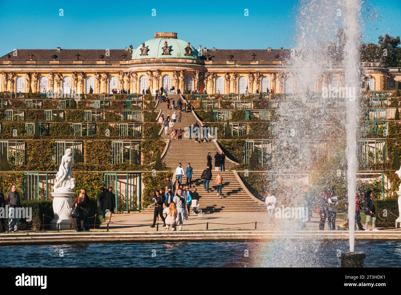 An einem klaren Herbsttag genießen die Besucher die elegante Fassade und die Terrassengärten des Schlosses Sanssouci in Potsdam Stockfoto