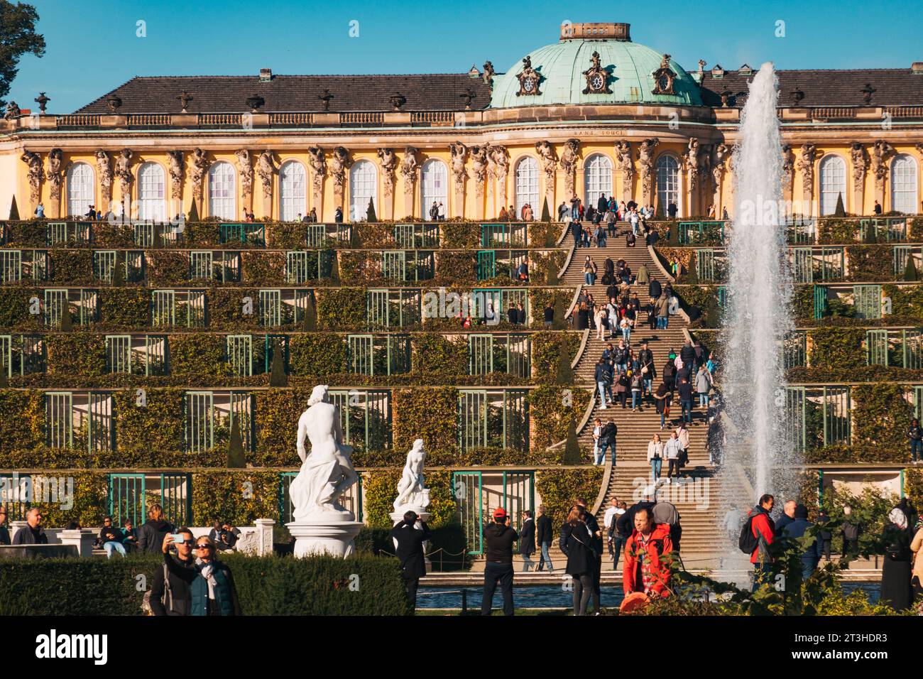 An einem klaren Herbsttag genießen die Besucher die elegante Fassade und die Terrassengärten des Schlosses Sanssouci in Potsdam Stockfoto