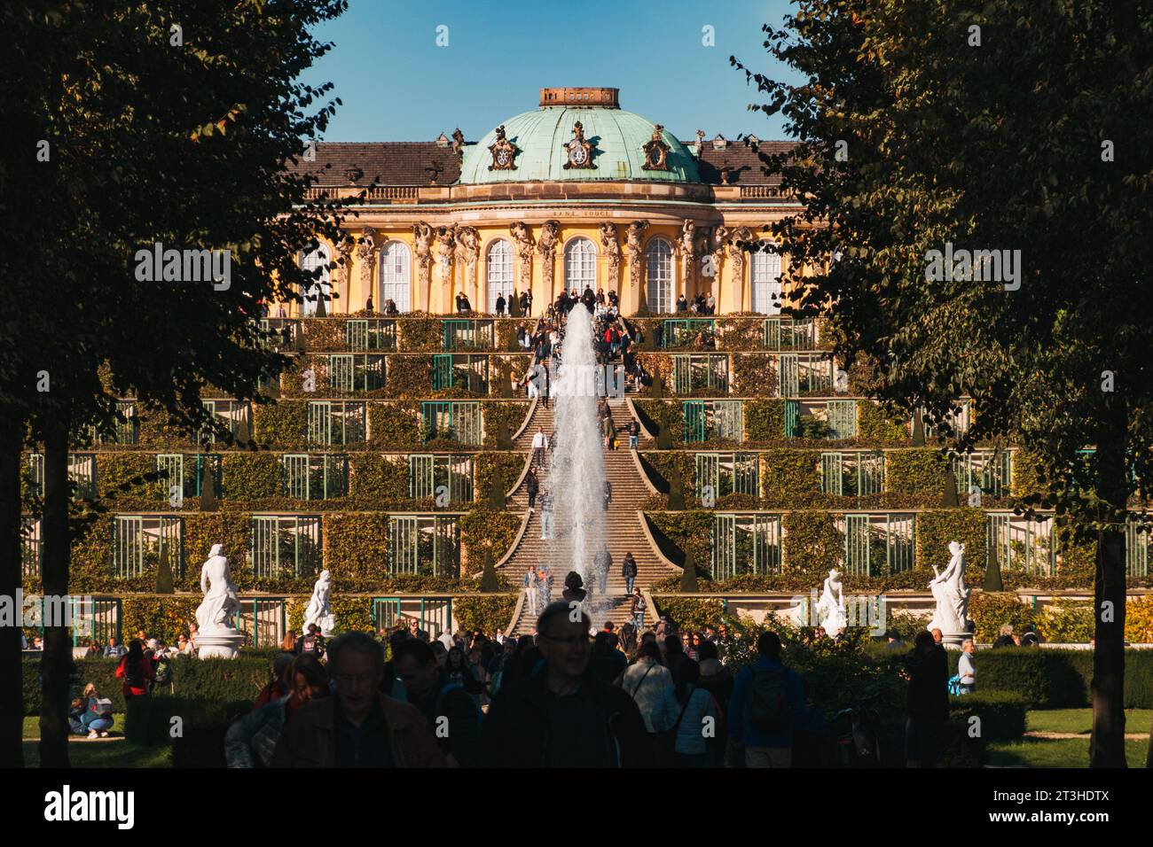 An einem klaren Herbsttag genießen die Besucher die elegante Fassade und die Terrassengärten des Schlosses Sanssouci in Potsdam Stockfoto