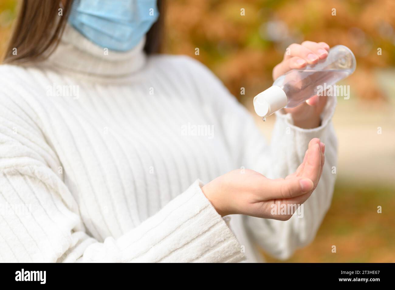 Frau mit medizinischer Schutzmaske, die antiseptisch ansetzt, um ihre Hände zu desinfizieren Stockfoto