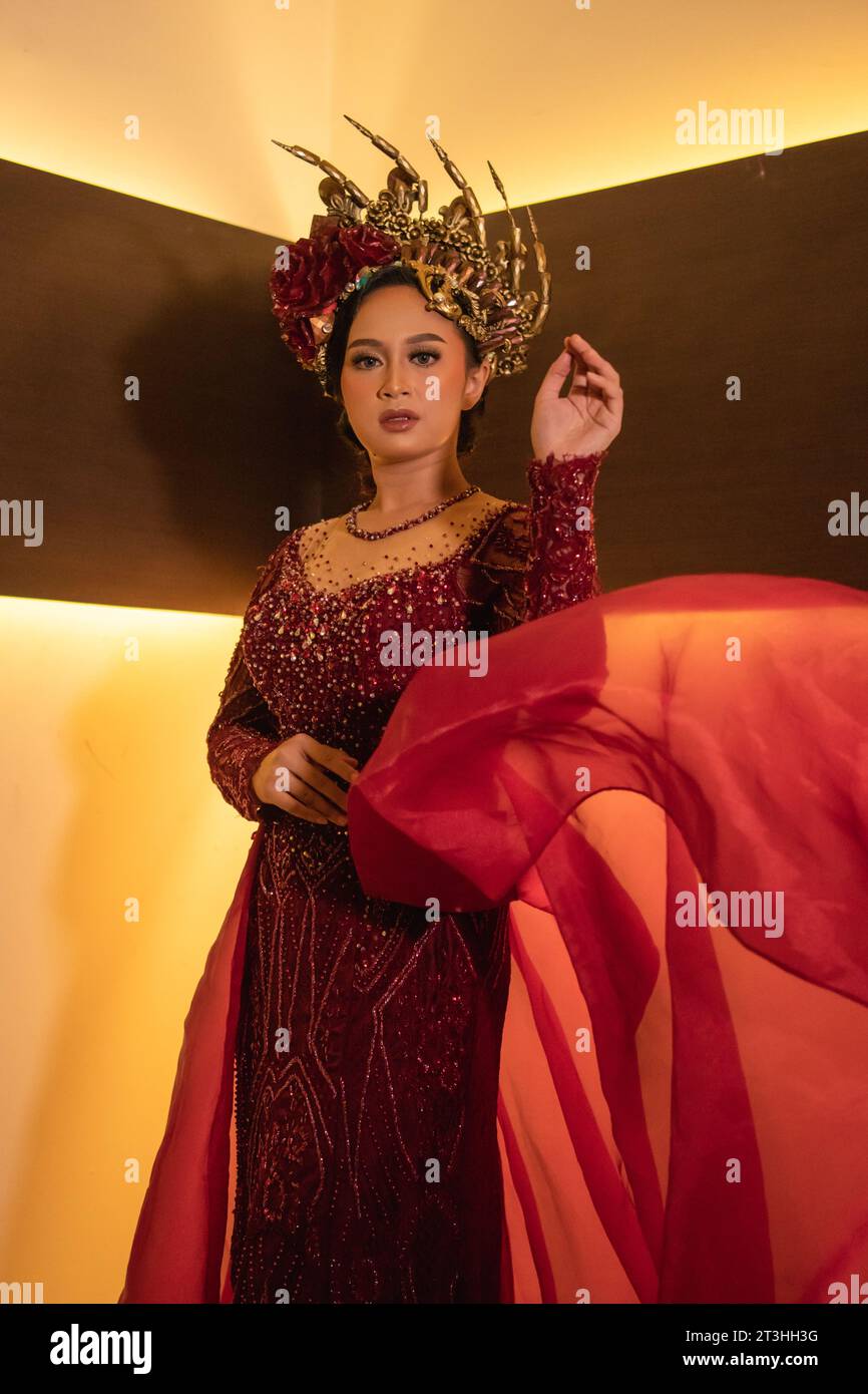 Eine schöne asiatische Frau schwingt den roten Stoffschwanz, während sie vor der Hochzeitszeremonie ein rotes Hochzeitskleid trägt Stockfoto