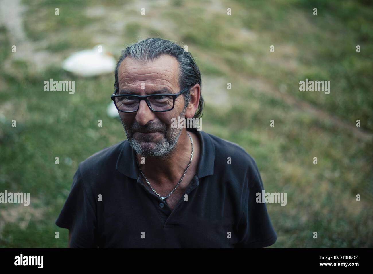 Im Freien schwelgt ein lebhafter serbischer Herr von 60 Jahren mit Brille und fließenden Schlössern in lebhaften Gesprächen und strahlt ein fröhliches Grinsen aus Stockfoto