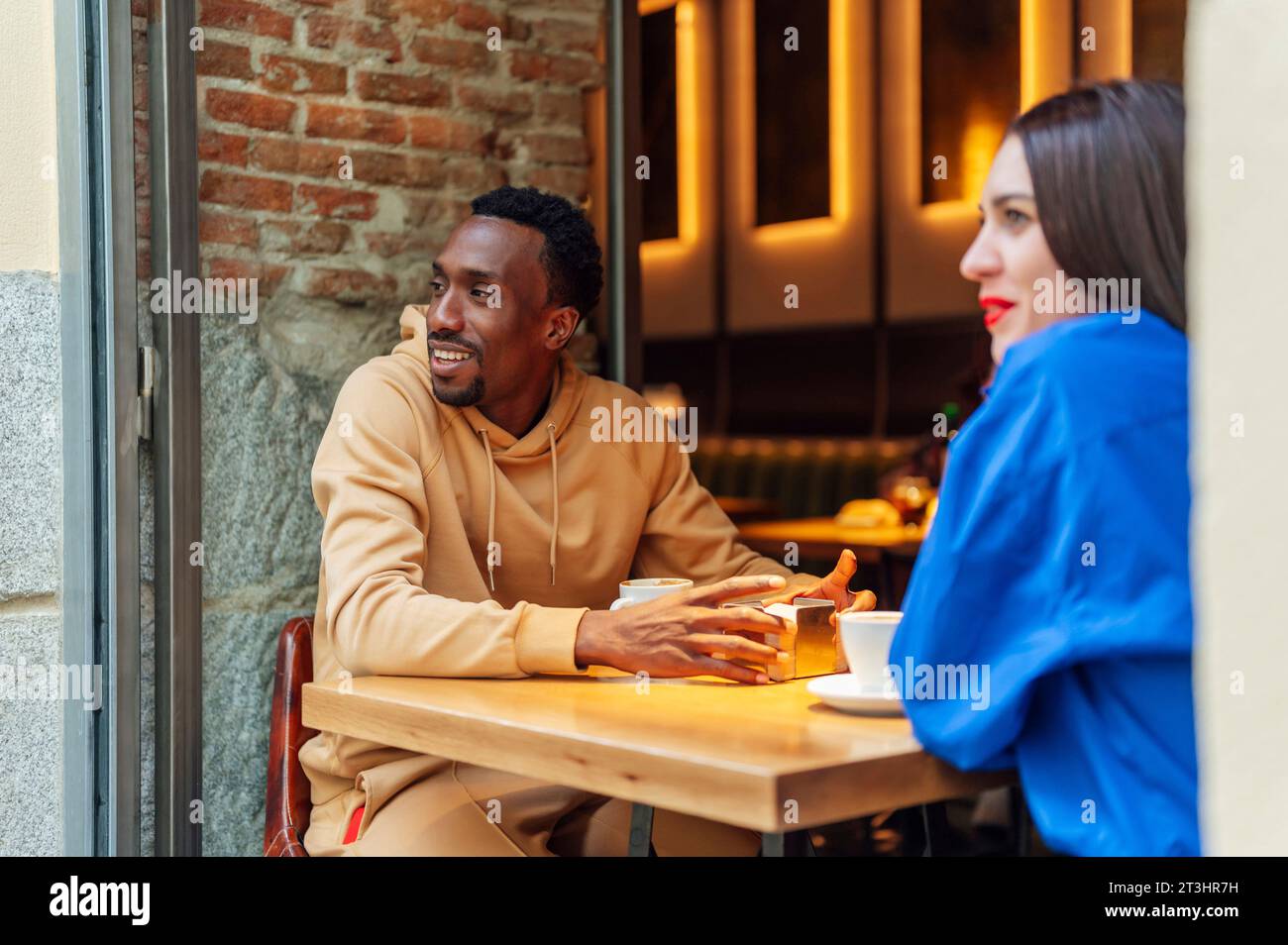 Zwei multiethnische Freunde, die gemeinsam einen Kaffee genießen, sitzen an einem Tisch Stockfoto