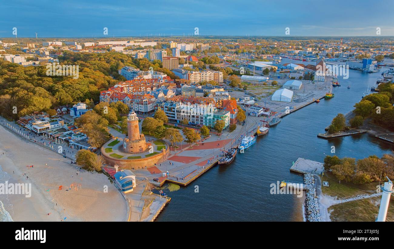 Das Drohnenfoto fängt Kołobrzeg maritimen Charme ein, mit dem berühmten Leuchtturm, dem braunen Meer, turbulenten Wellen und einem entfernten Pier. Stockfoto
