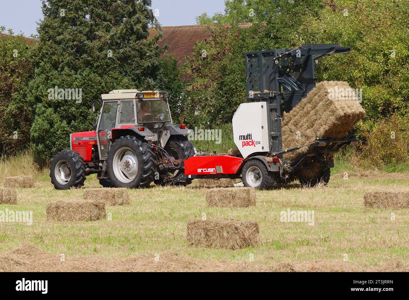 Die Multipack-Ballenpresse Arcusin D14 gibt einen großen gebundenen Heuballen aus 14 einzelnen rechteckigen Ballen frei. angetrieben von einem Massey Ferguson 390T-Traktor. Stockfoto