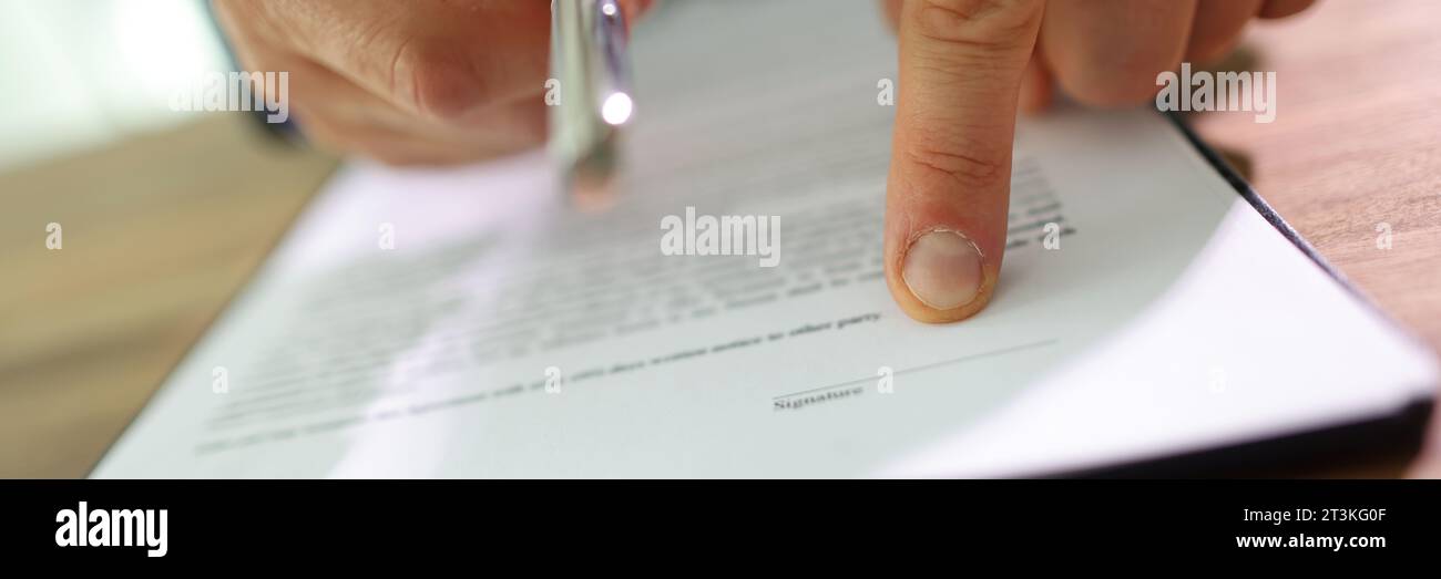 Der Manager zeigt mit dem Finger auf die Linie auf dem Vertragspapier, das den Stift ausgibt Stockfoto