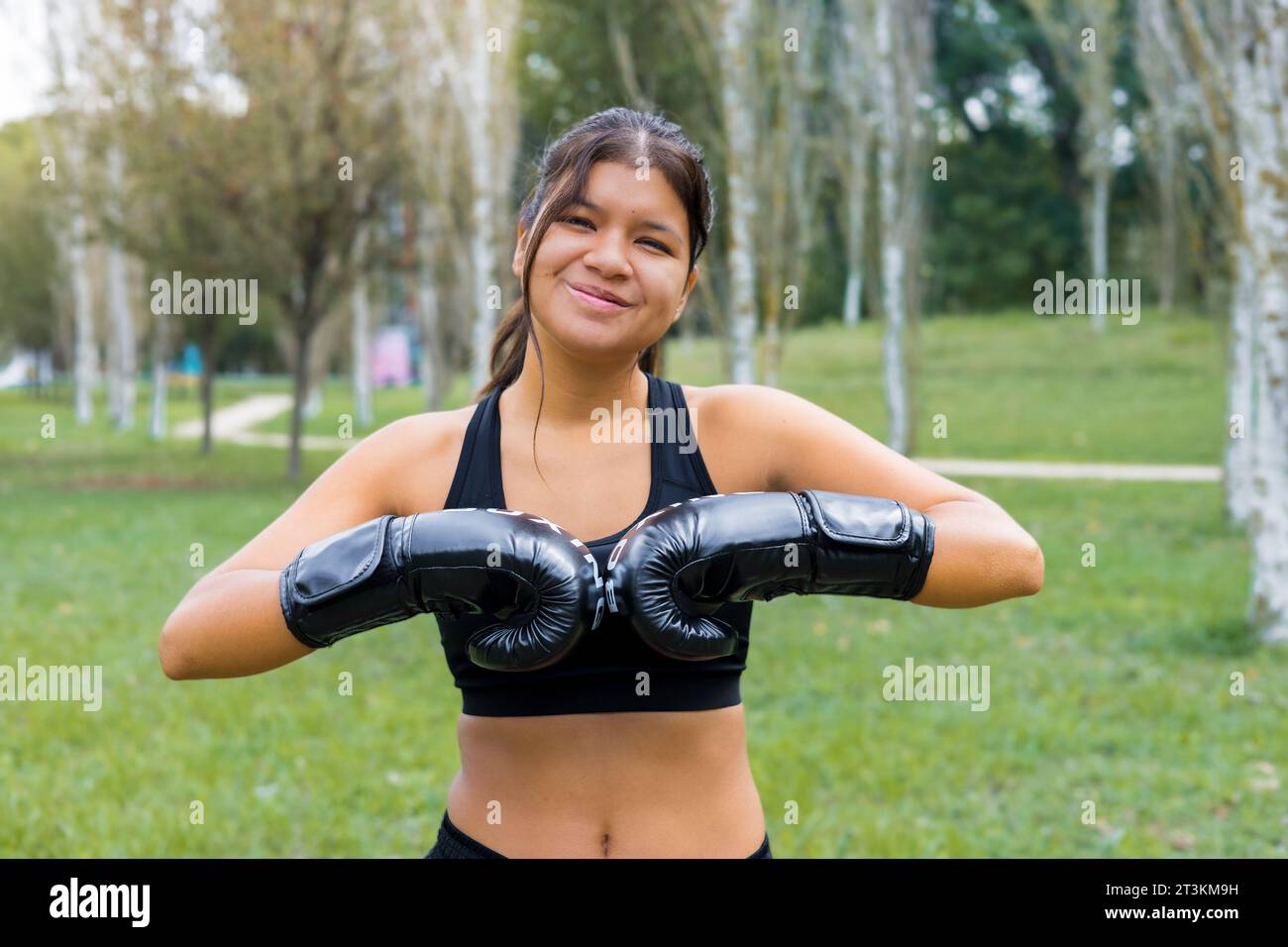 Junge lateinboxerin, die Boxhandschuhe in einem Outdoor-Sparringtraining anzieht Stockfoto