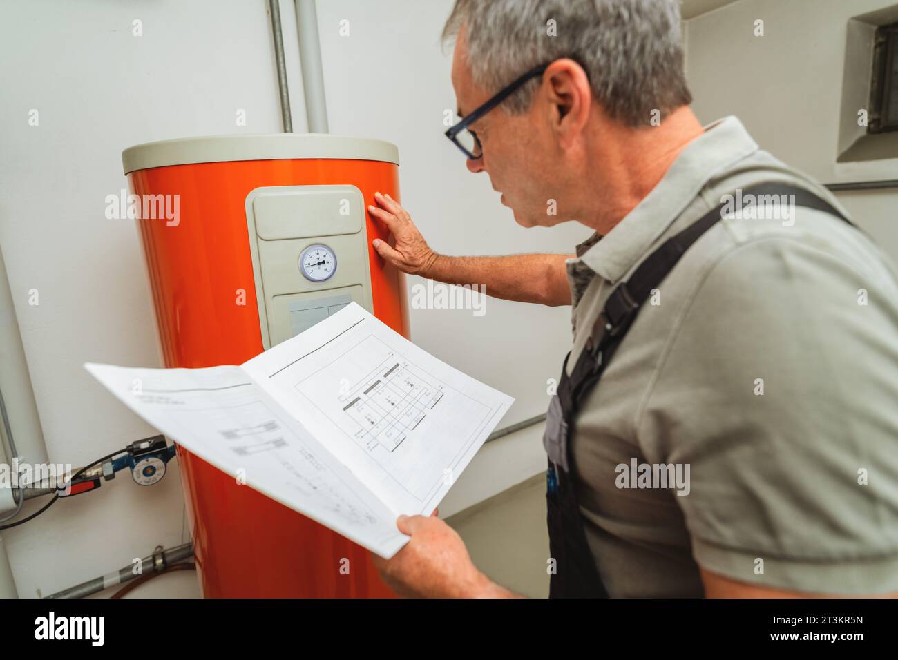 Heizungsingenieure überprüfen eine alte Gasheizung mit einer Papieranweisung in einem Heizraum in einem Haus. Konzept für den Austausch von Gasheizgeräten, Abb. Stockfoto