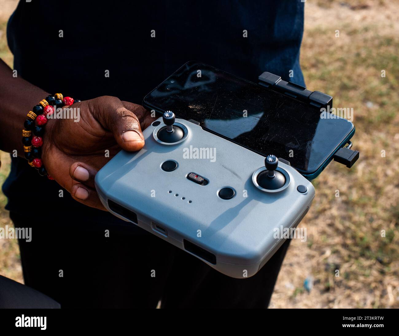 Mann, der eine Drohne mit Fernbedienung mit angeschlossenem Mobiltelefon bedient Stockfoto