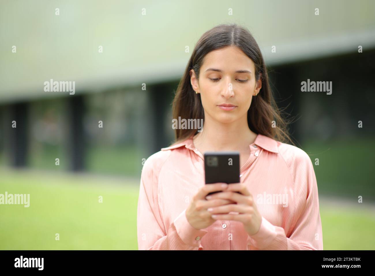 Vorderansicht Porträt einer ernsten Frau, die ein Handy benutzt, das auf Sie zugeht Stockfoto