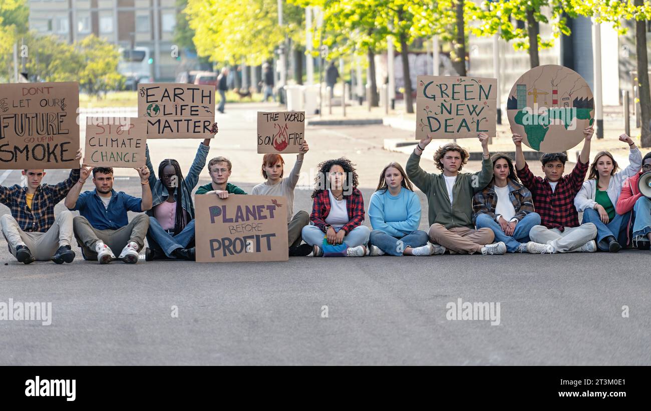 Umweltaktivisten protestieren für Veränderung - Eine Gruppe von Aktivisten versammelt sich in einem städtischen Umfeld und hält Schilder, die Maßnahmen gegen das Klima fordern Stockfoto