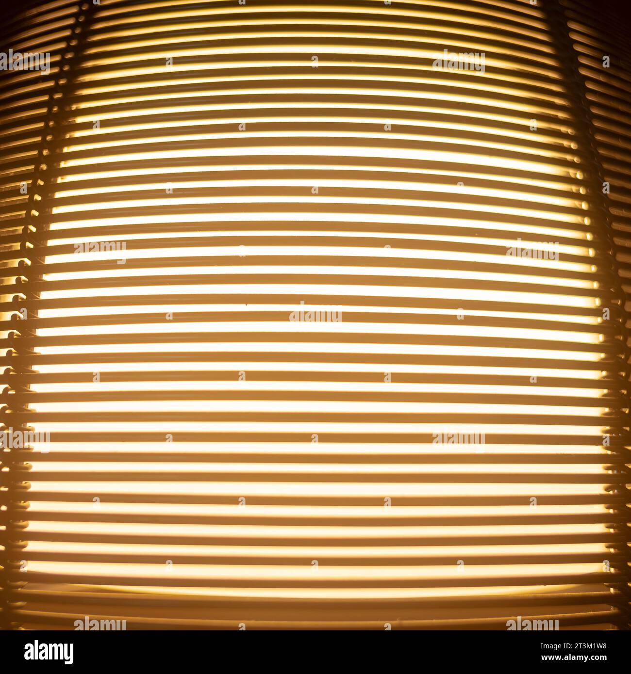 Licht scheint durch die Zwischenräume von übereinander liegenden Holzlatten eines Lampenschirms, Musters und Hintergrunds. Stockfoto