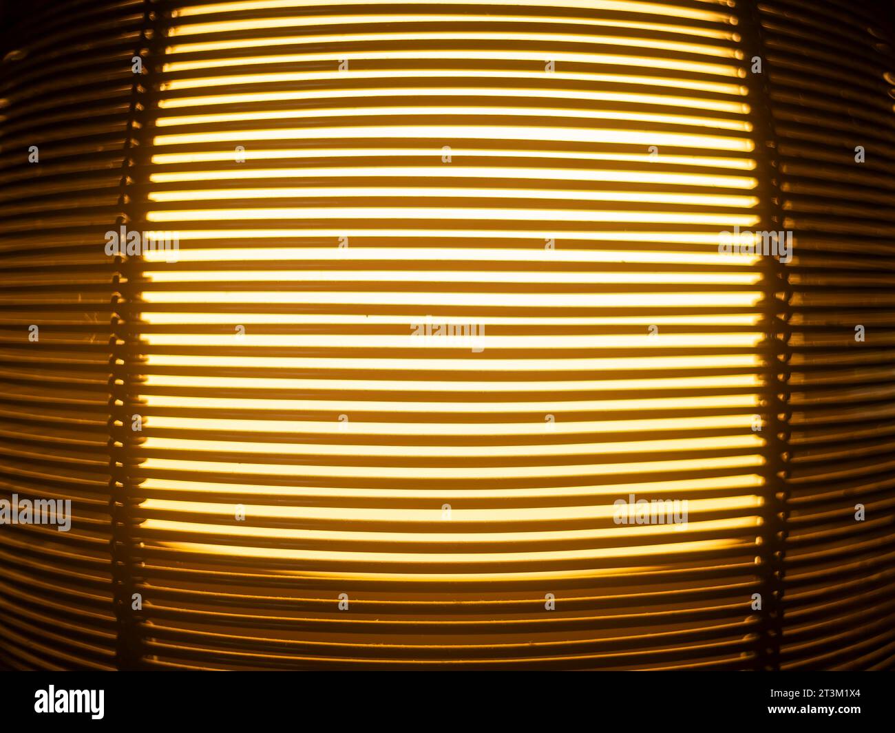 Licht scheint durch die Zwischenräume von übereinander liegenden Holzlatten eines Lampenschirms, Musters und Hintergrunds. Stockfoto