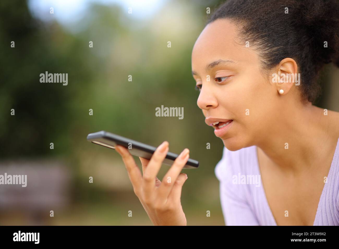 Schwarze Frau diktiert eine Nachricht am Telefon in einem Park Stockfoto