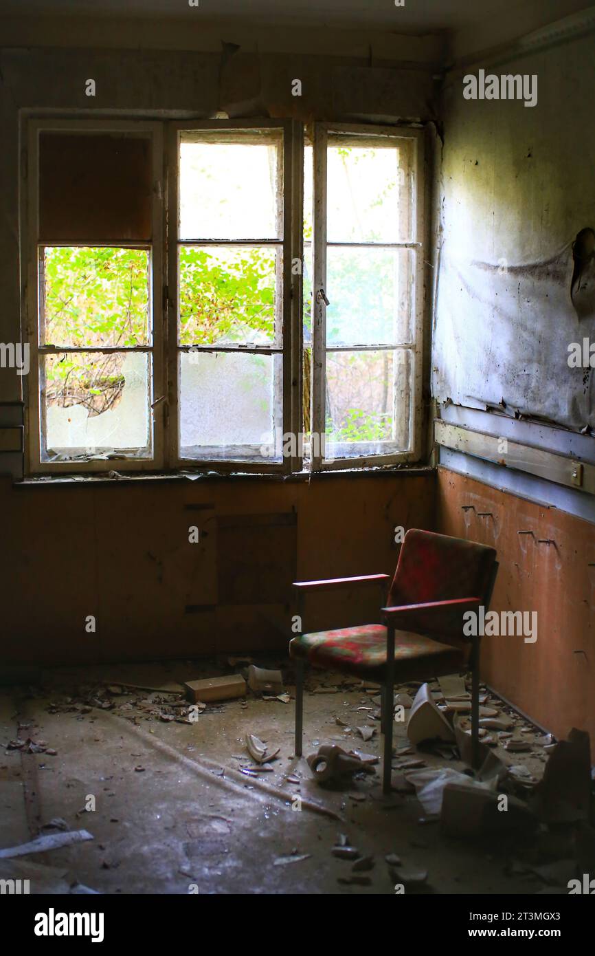 Sessel zwischen Trümmern vor einem kaputten Fenster. Stockfoto