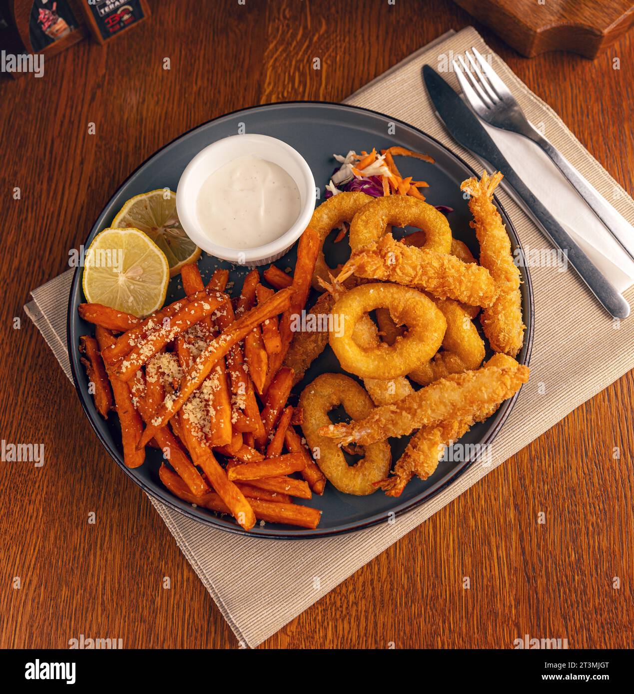 Blick von oben auf frittierte Meeresfrüchte, serviert mit Süßkartoffeln und Sauce Stockfoto