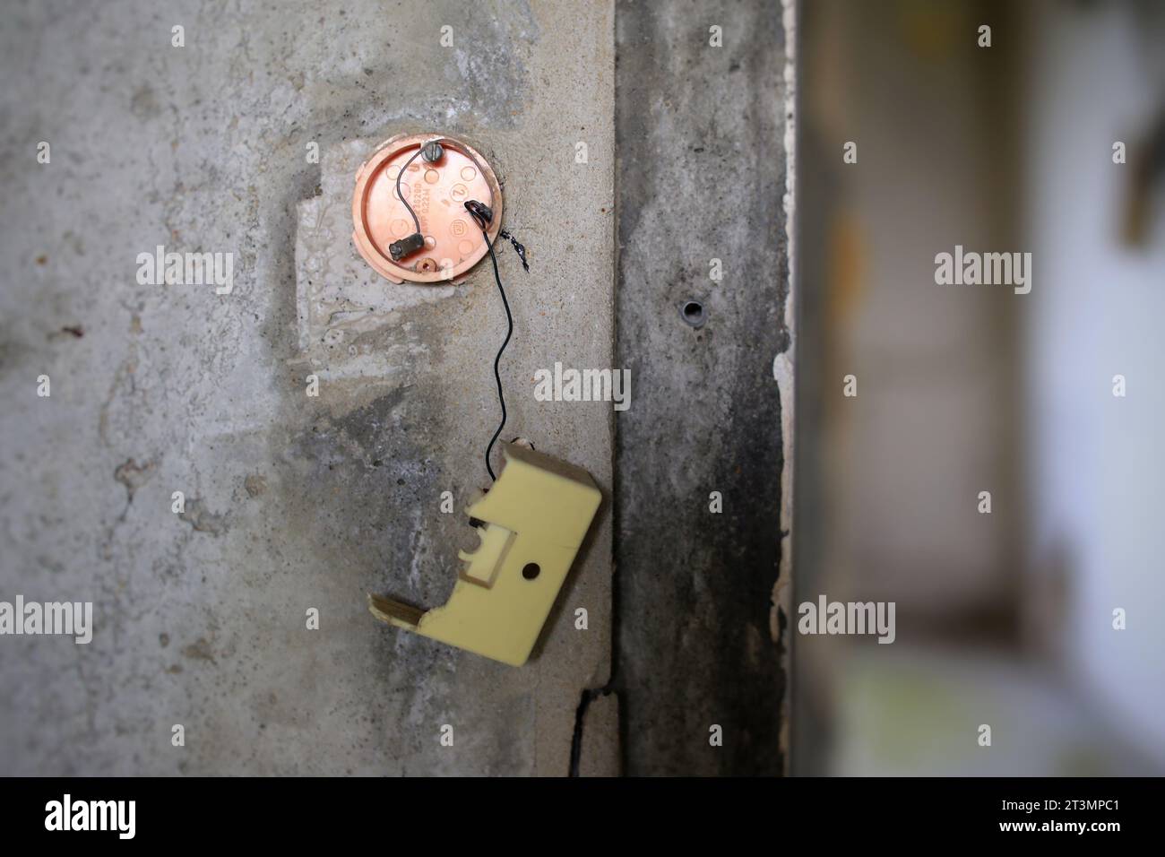 Defekter Lichtschalter an einer Betonwand. Stockfoto