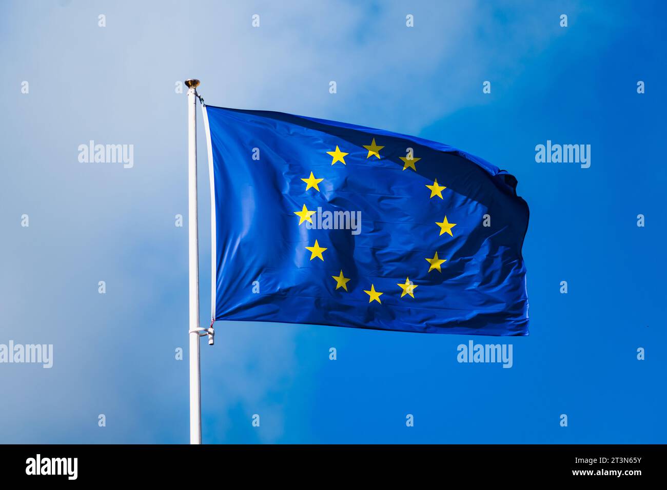 Europaflagge flattert mit starkem Wind und blauem Himmel, blaue Flagge mit gelben Sternen, die einen Kreis bilden Stockfoto