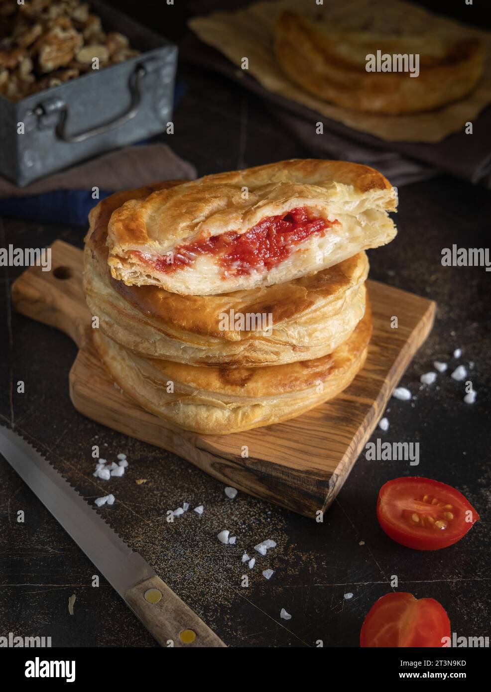 Rustico traditioneller Blätterteig gefüllt mit Bechamelsauce, Tomaten und Mozzarella, Nahaufnahme auf einem dunklen Tisch. Traditionelles Street Food aus Sal Stockfoto