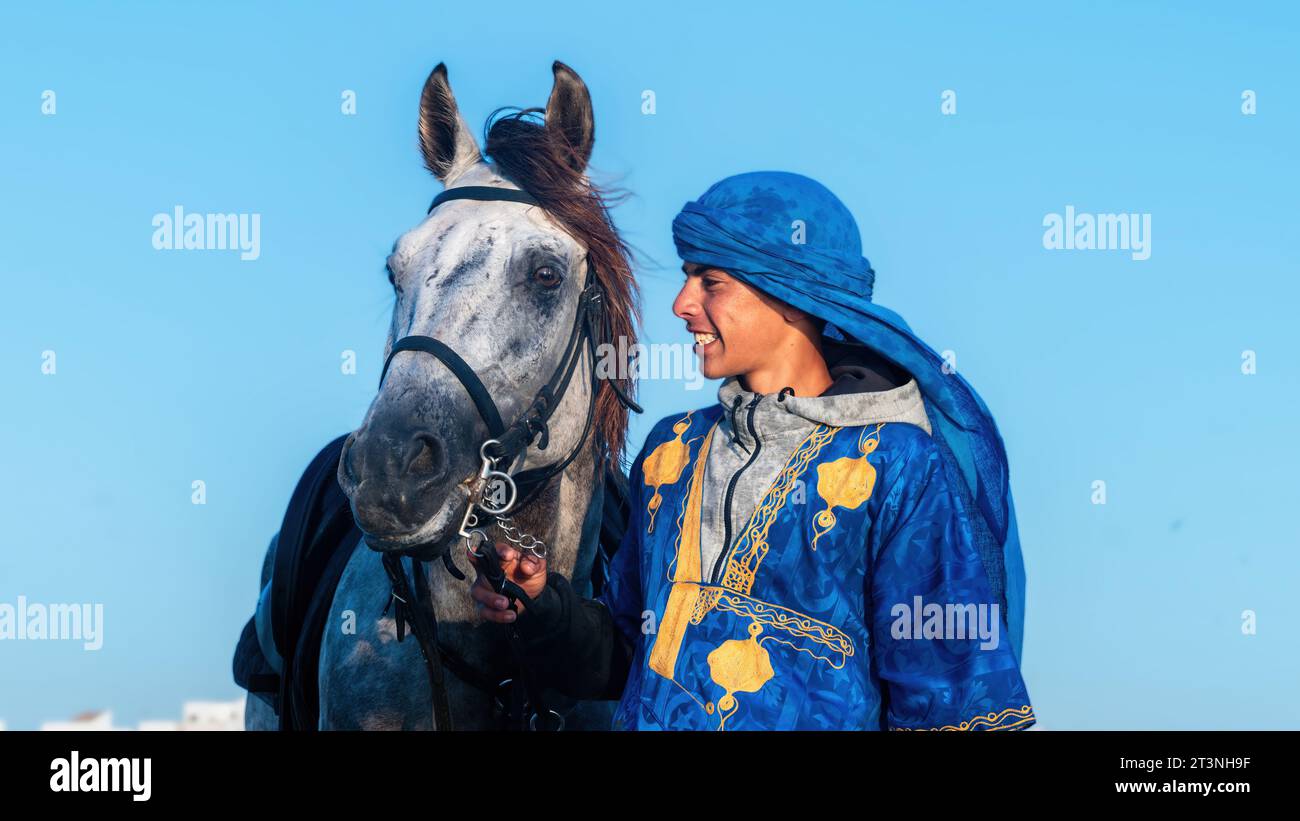 Essaouira, Marokko – 16. September 2022: Junger Berbermann mit seinem Pferd, zusammen mit einem Band des Vertrauens und der Gesellschaft. Stockfoto