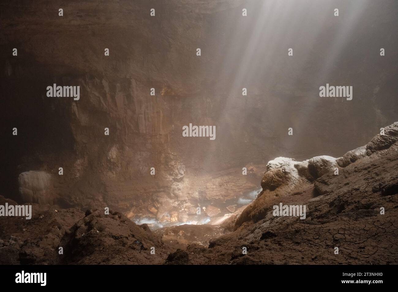 Tauchen Sie ein in das bezaubernde Ambiente der Höhle Jomblang, während ätherische Lichtstrahlen den bräunlichen Steinboden der Höhle sanft streicheln. Stockfoto