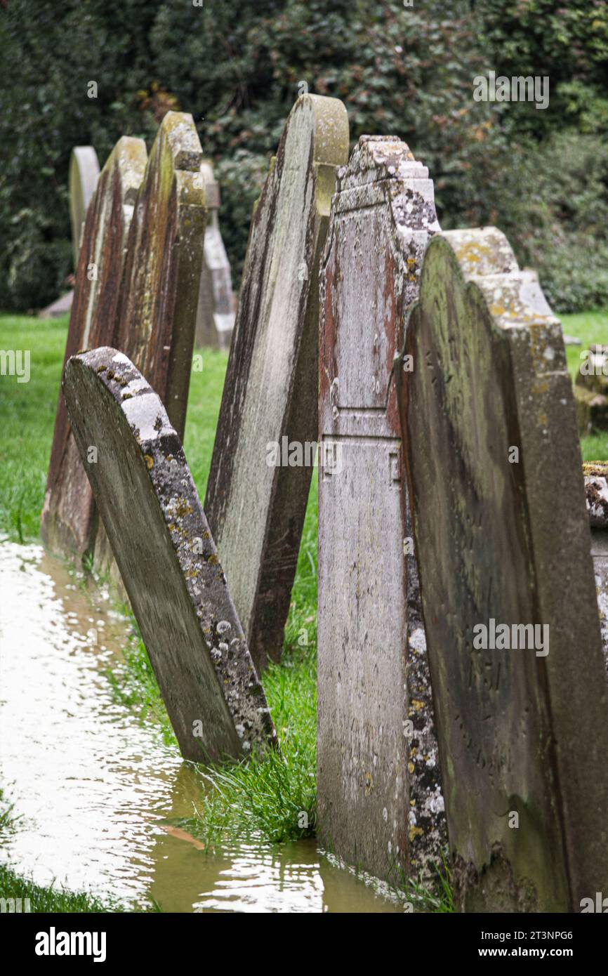 Ein überfluteter Kirchenfriedhof mit Grabsteinen, die umkippen Stockfoto