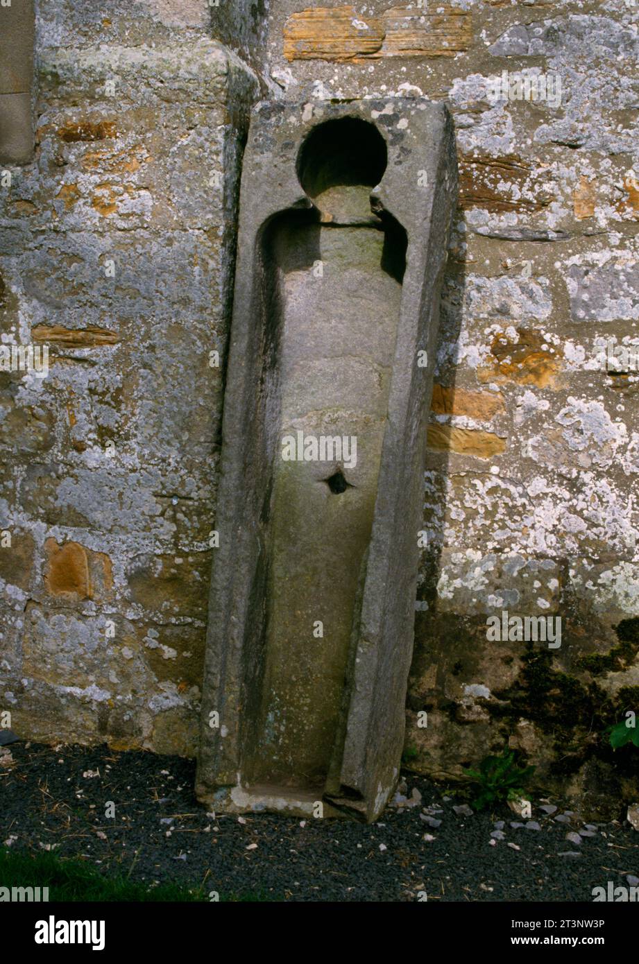 Der südliche von zwei mittelalterlichen Steinsärgen, die an der westlichen Außenwand der St Cuthbert’s Church in Elsdon, Northumberland, England, Großbritannien, anlehnen. Stockfoto